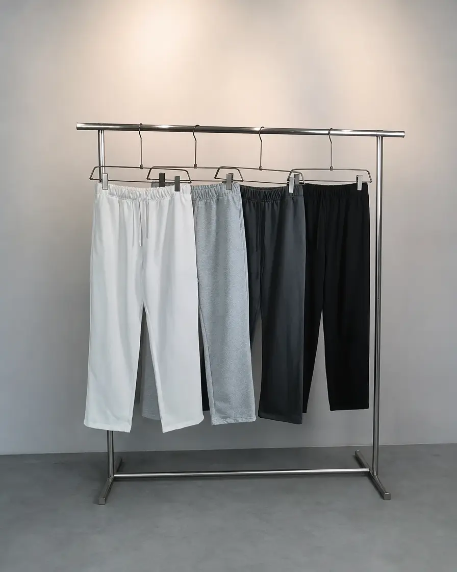 Custom sweatpants in white, grey, charcoal and black on a clothing rack at Garment Simple